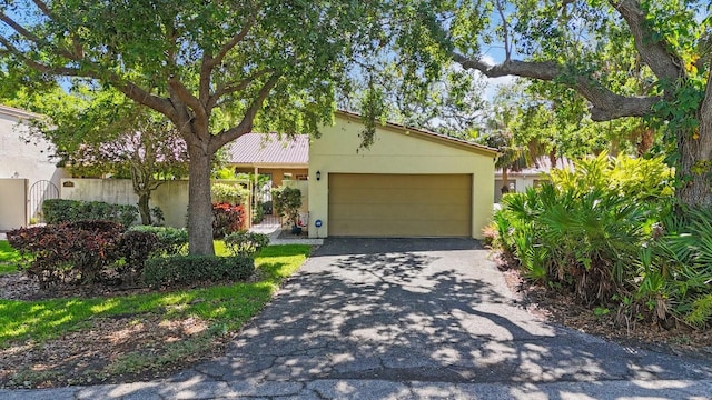 view of front of home with aphalt driveway, fence, and stucco siding