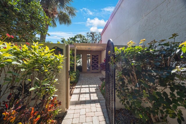 entrance to property with stucco siding and a gate