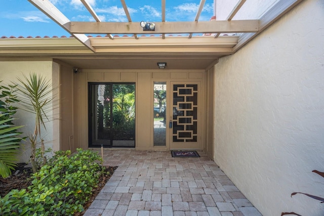 view of exterior entry featuring a patio area and stucco siding