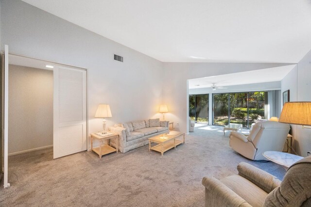 carpeted living room with visible vents, vaulted ceiling, and a ceiling fan
