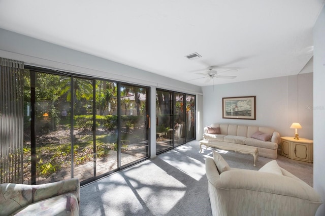 carpeted living area with visible vents, a ceiling fan, and plenty of natural light
