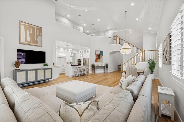4013 Red Rock Ln, Sarasota, FL 34231 - living room featuring high vaulted ceiling, stairway, a ceiling fan, light wood-style floors, and arched walkways