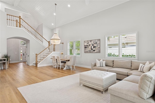 4013 Red Rock Ln, Sarasota, FL 34231 - living room featuring arched walkways, high vaulted ceiling, light wood finished floors, stairway, and baseboards