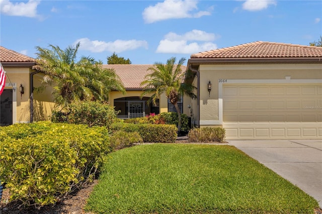 2064 Batello Dr, Venice, FL 34292 - mediterranean / spanish-style home with a tiled roof, concrete driveway, a front yard, stucco siding, and an attached garage