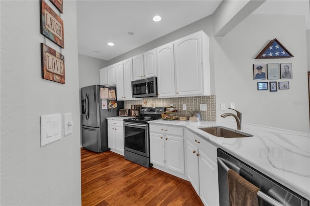 2064 Batello Dr, Venice, FL 34292 - kitchen featuring appliances with stainless steel finishes, a sink, light stone counters, dark wood-style flooring, and backsplash