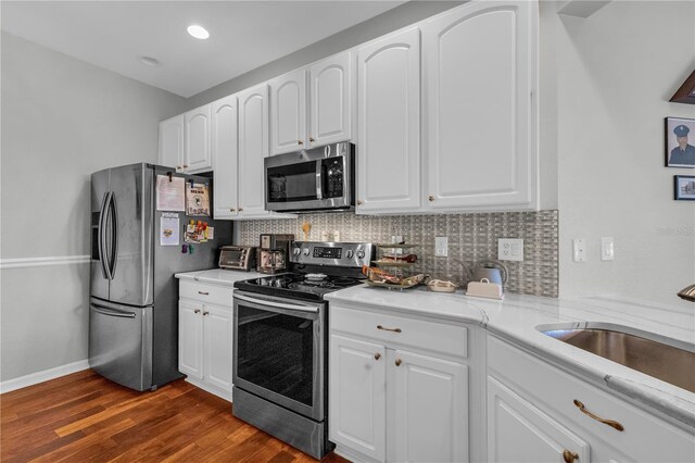 2064 Batello Dr, Venice, FL 34292 - kitchen featuring appliances with stainless steel finishes, dark wood-style floors, backsplash, white cabinetry, and a sink