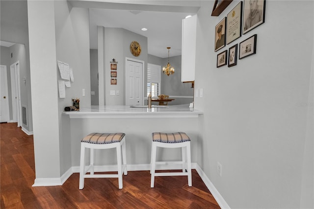 2064 Batello Dr, Venice, FL 34292 - kitchen featuring a kitchen bar, dark wood-style flooring, a chandelier, baseboards, and light countertops