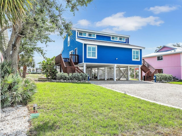 21687/689 Indian Bayou Dr, Fort Myers Beach, FL 33931 - raised beach house featuring gravel driveway, stairs, a front yard, and a carport