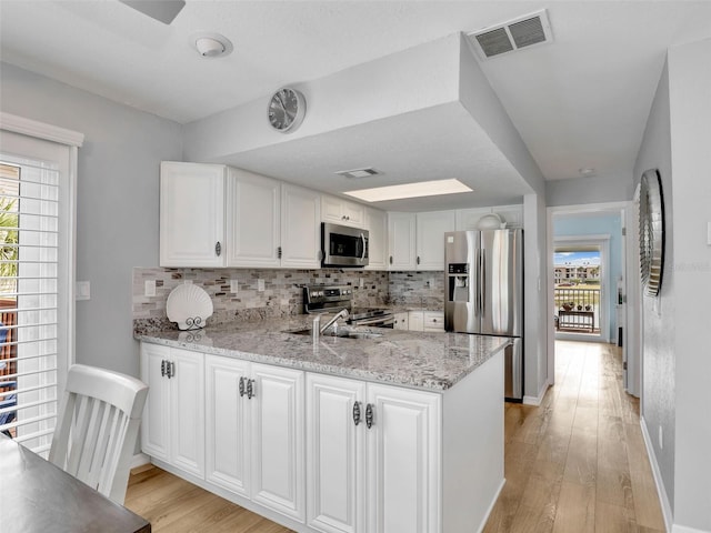 21687/689 Indian Bayou Dr, Fort Myers Beach, FL 33931 - kitchen featuring white cabinets, light wood-style flooring, appliances with stainless steel finishes, and visible vents