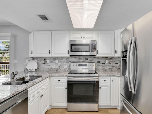 21687/689 Indian Bayou Dr, Fort Myers Beach, FL 33931 - kitchen with backsplash, a sink, stainless steel appliances, visible vents, and white cabinets
