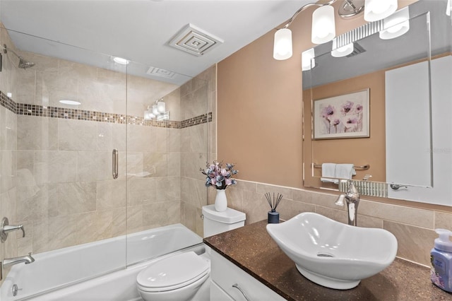 1233 Dockside Pl Unit 207, Sarasota, FL 34242 - full bathroom with toilet, tile walls, vanity, bath / shower combo with glass door, and a wainscoted wall