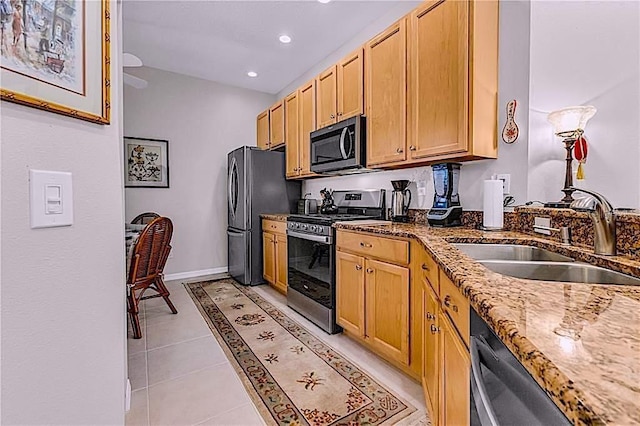 4136 Cascade Falls Dr, Sarasota, FL 34243 - kitchen featuring appliances with stainless steel finishes, a sink, dark stone countertops, light brown cabinetry, and light tile patterned floors