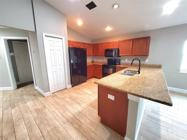 kitchen featuring a sink, black appliances, light wood-type flooring, and a peninsula