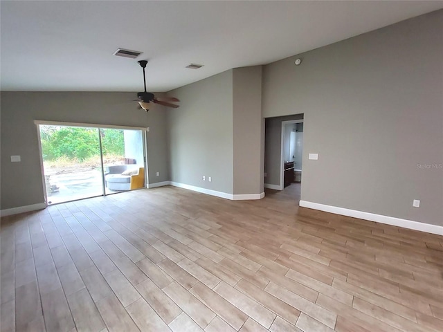 spare room featuring a ceiling fan, wood finished floors, lofted ceiling, baseboards, and visible vents