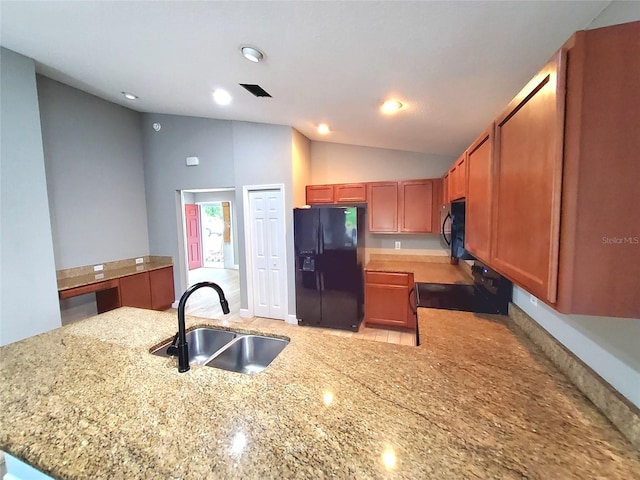 kitchen with light stone counters, a sink, a peninsula, lofted ceiling, and black appliances