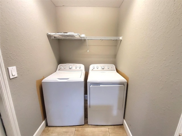 laundry room featuring laundry area, light tile patterned floors, baseboards, washer and dryer, and a textured wall