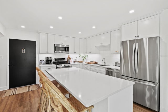 kitchen with stainless steel appliances, a sink, backsplash, a kitchen island, and recessed lighting