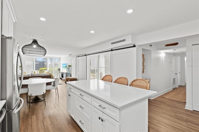 kitchen with freestanding refrigerator, light wood-style flooring, white cabinets, light countertops, and a kitchen island