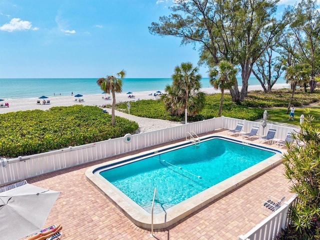community pool featuring a water view, a patio area, and fence