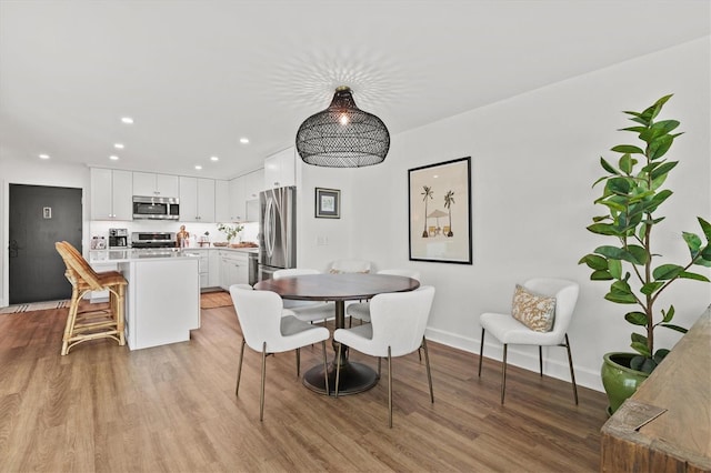 dining area with light wood-type flooring, baseboards, and recessed lighting