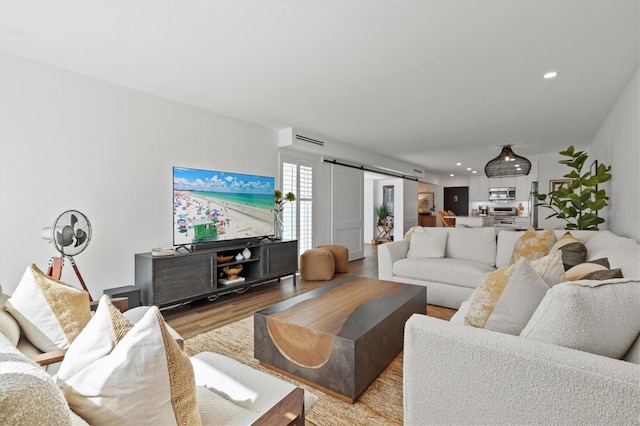 living area featuring a barn door, wood finished floors, and recessed lighting