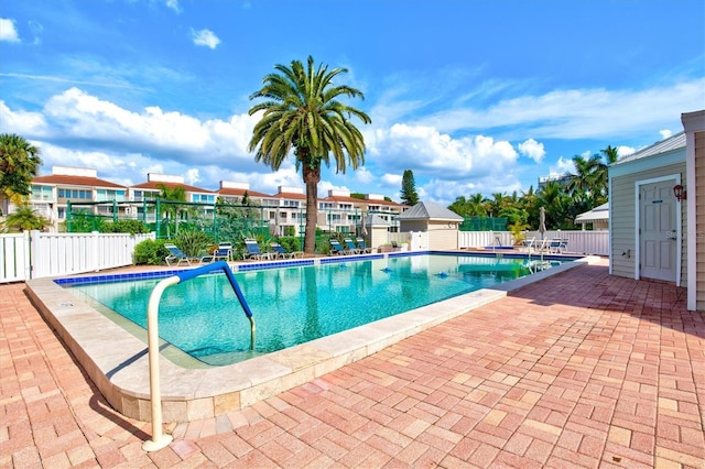 community pool with fence and a patio area