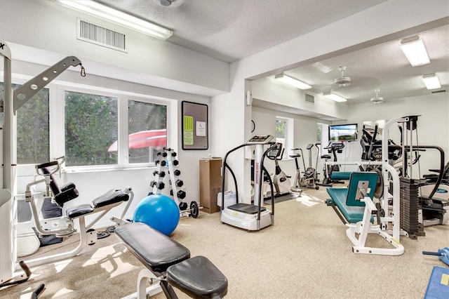 gym featuring a ceiling fan, carpet floors, and a textured ceiling