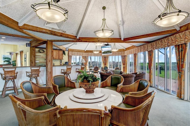 carpeted dining area with beamed ceiling