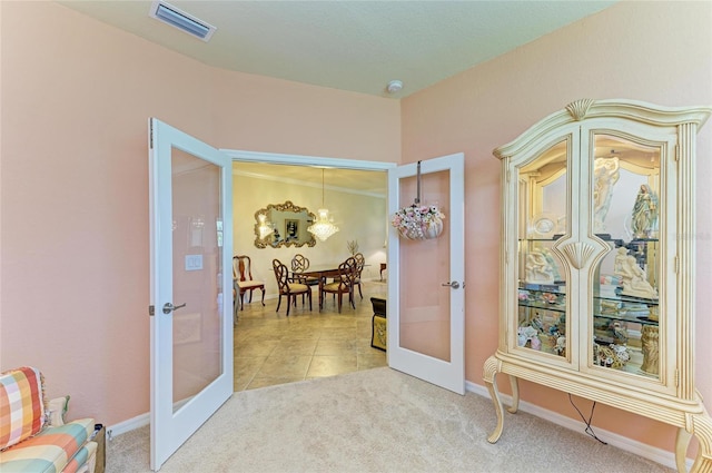 19889 Benissimo Dr, Venice, FL 34293 - hall with french doors, an inviting chandelier, light tile patterned flooring, visible vents, and light carpet
