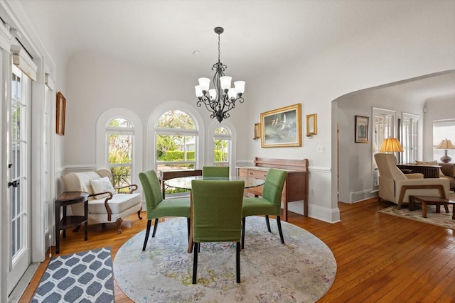 dining space with light wood finished floors, baseboards, and an inviting chandelier