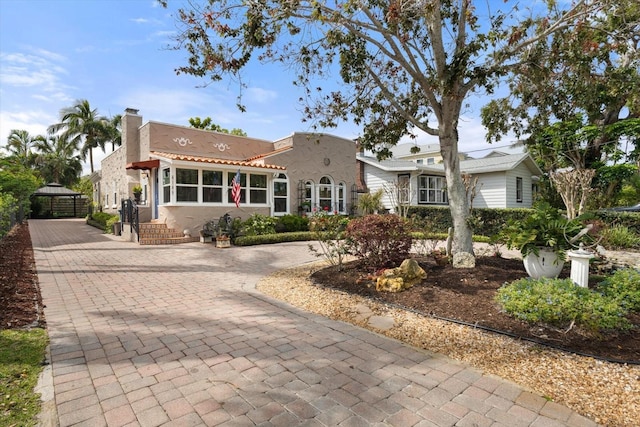 view of front of property with decorative driveway, stucco siding, and a chimney
