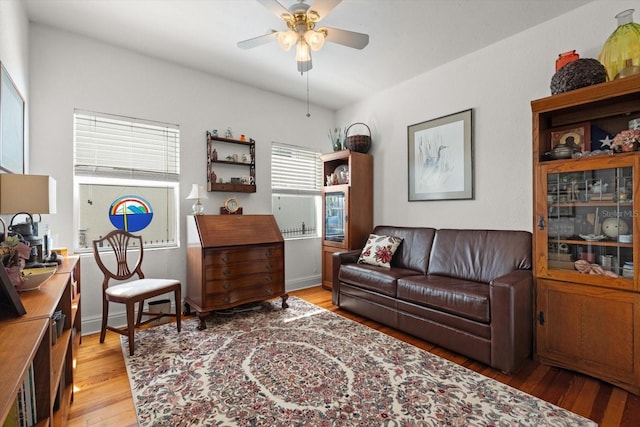 living area with a ceiling fan, light wood-style flooring, and baseboards
