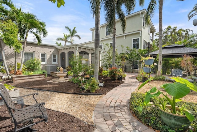 back of property featuring central AC unit, a gazebo, stucco siding, and fence