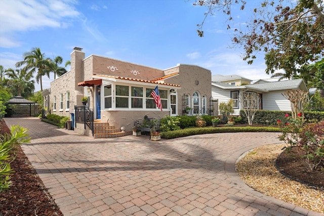 view of front of home featuring a chimney and stucco siding