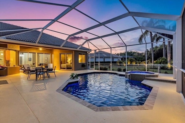 pool at dusk with outdoor dining space, a pool with connected hot tub, and a patio area