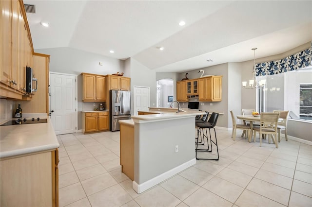 kitchen with a kitchen island with sink, light tile patterned floors, lofted ceiling, a breakfast bar, and stainless steel appliances