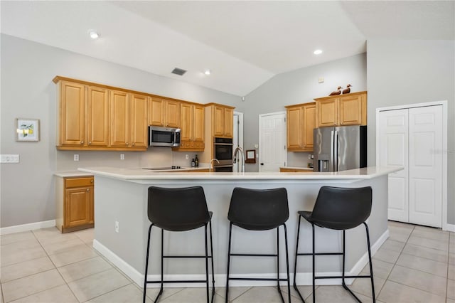 kitchen featuring stainless steel appliances, light tile patterned floors, lofted ceiling, and a kitchen bar