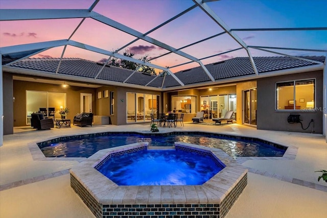 pool at dusk featuring a patio, a pool with connected hot tub, a ceiling fan, and outdoor dining space