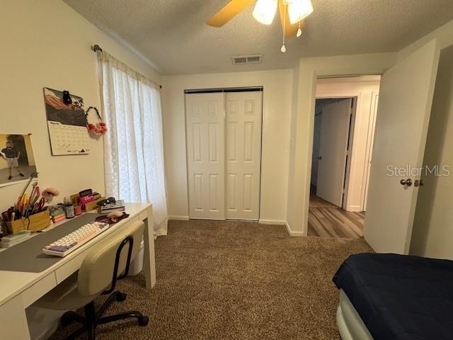 831 Bacon Ave, Sarasota, FL 34232 - bedroom with a closet, a textured ceiling, visible vents, ceiling fan, and dark colored carpet