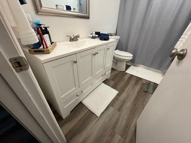 831 Bacon Ave, Sarasota, FL 34232 - full bathroom featuring toilet, vanity, a shower with shower curtain, and wood finished floors