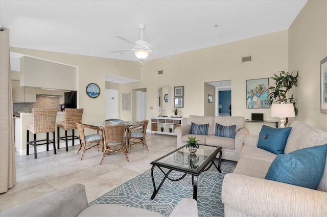 living room with a ceiling fan, a high ceiling, and visible vents
