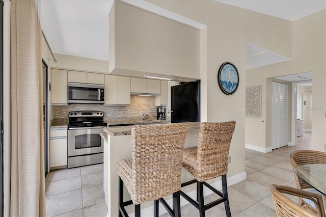 kitchen with stainless steel appliances, a sink, light tile patterned floors, and tasteful backsplash