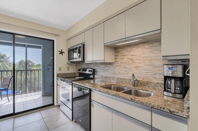 kitchen with appliances with stainless steel finishes, decorative backsplash, a sink, and light stone counters