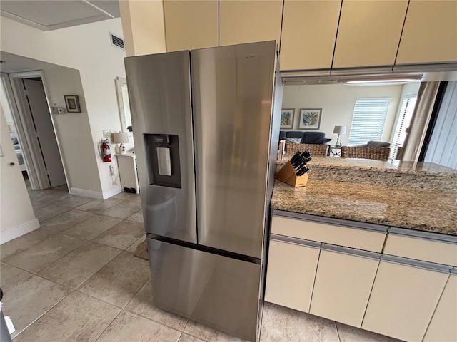 kitchen featuring visible vents, light tile patterned floors, light stone counters, baseboards, and stainless steel fridge