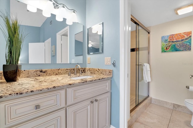 bathroom with ceiling fan, tile patterned flooring, a shower stall, vanity, and toilet