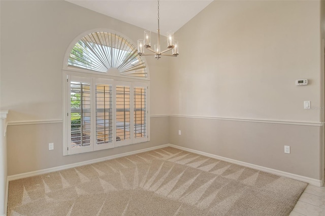 carpeted spare room with baseboards, high vaulted ceiling, and a notable chandelier
