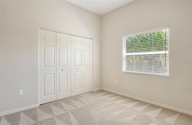 unfurnished bedroom with light carpet, a closet, and baseboards