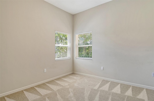 spare room featuring baseboards and light colored carpet