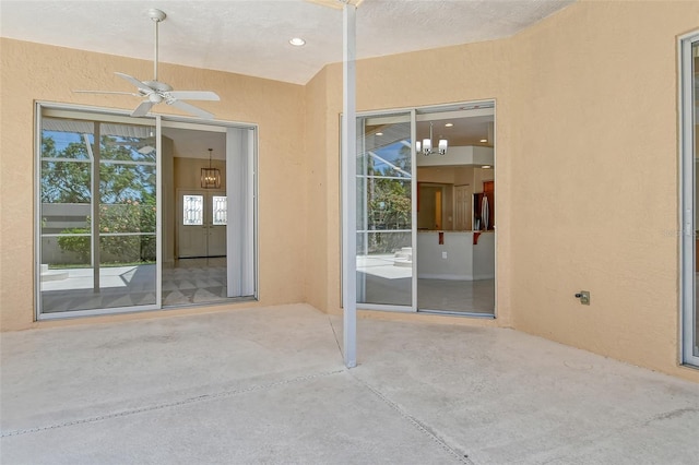 entrance to property featuring a ceiling fan, a patio, and stucco siding