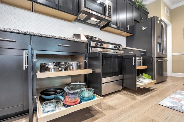 2628 Sapphire Blue Ln, Bradenton, FL 34211 - kitchen featuring stainless steel appliances, ornamental molding, light wood finished floors, dark cabinetry, and light countertops